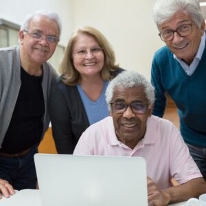 group of elderly people standing behind a laptop and smiling